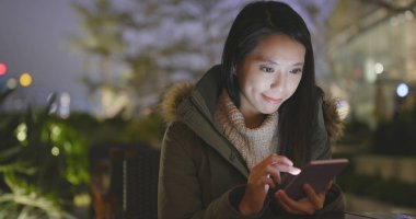 Geceleri cep telefonu kullanan bir kadın. 