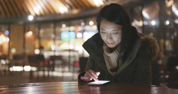 Woman using mobile phone outside restaurant at night