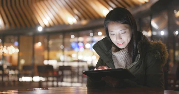 Woman using smartphone outside restaurant at night