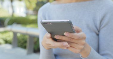 Parkta akıllı telefon kullanan kadın. 