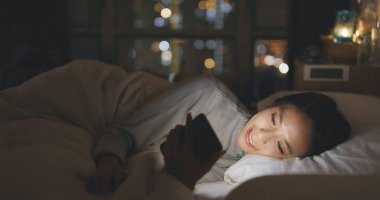 Cep telefonu kullanarak ve geceleri yatakta yatarken kadın 