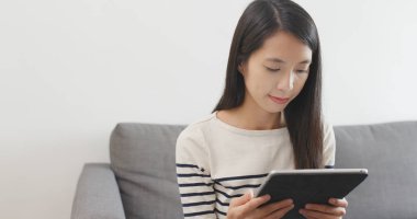 Tablet bilgisayar kullanarak ve koltukta oturan kadın 