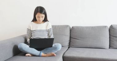 Dizüstü bilgisayar kullanan ve koltukta oturan kadın 