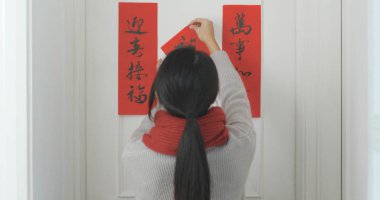 Woman sticking chinese calligraphy on the door  clipart