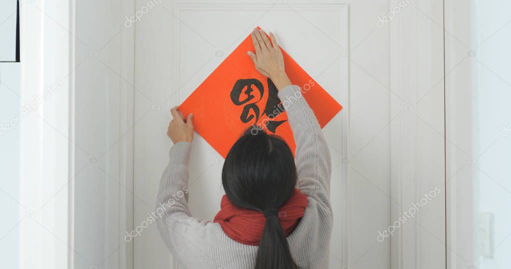 Woman sticking chinese calligraphy on the door for lunar new year