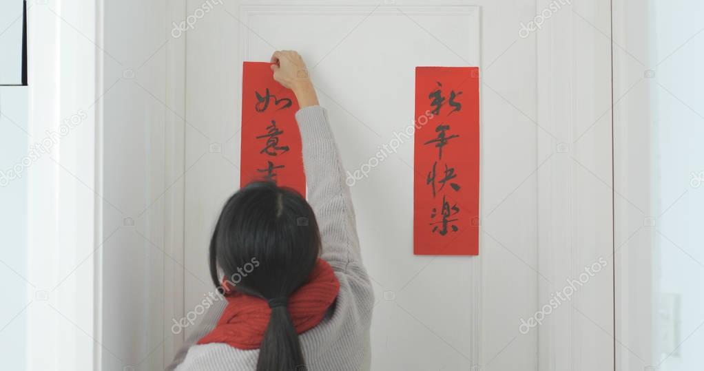 Woman sticking chinese calligraphy on the door 