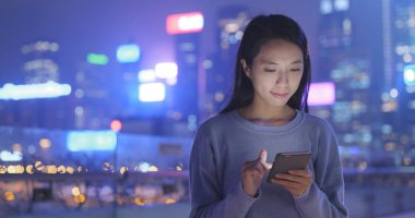 Gece şehirde akıllı telefon kullanan bir kadın. 