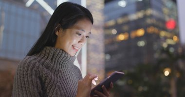 Geceleri cep telefonu kullanan bir kadın. 