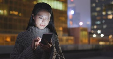 Geceleri cep telefonu kullanan bir kadın. 