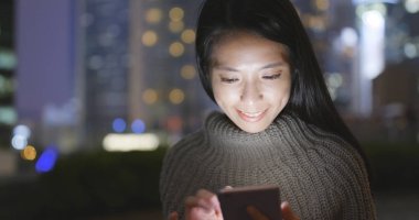 Gece akıllı telefon kullanan bir kadın. 