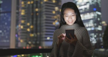 Geceleri cep telefonu kullanan bir kadın. 