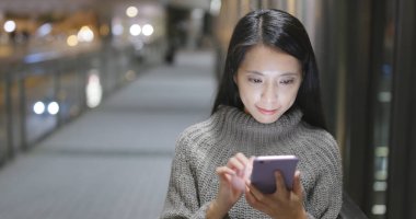 Genç kadın cep telefonuyla şehirde geceleri 