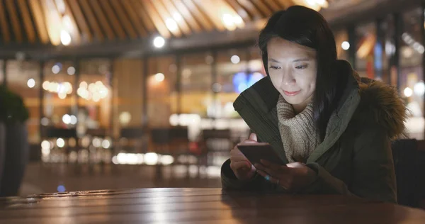 Woman using smartphone outside restaurant at night