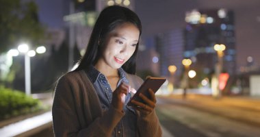 Geceleri cep telefonu kullanan bir kadın. 