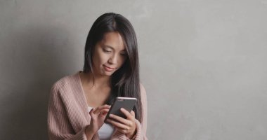 Gri arkaplan üzerinde akıllı telefon kullanan kadın 