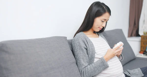 Pregnant woman taking supplement at home