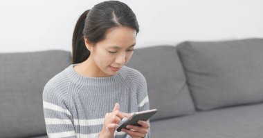 Evde cep telefonu kullanan bir kadın 