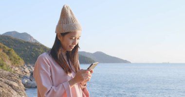 Deniz manzarası arka plan üzerinde cep telefonu kullanan kadın