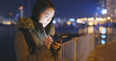 Geceleri cep telefonu kullanan bir kadın. 