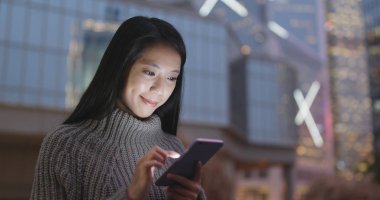 Geceleri cep telefonu kullanan bir kadın. 