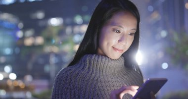 Geceleri cep telefonu kullanan bir kadın. 