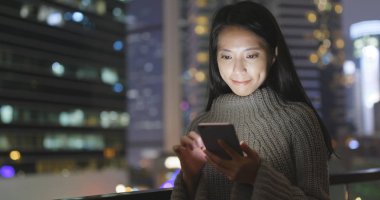 Geceleri cep telefonu kullanan bir kadın. 