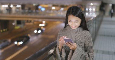 Gece şehirde akıllı telefon kullanan bir kadın.