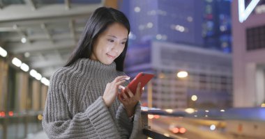 Genç kadın cep telefonuyla şehirde geceleri 