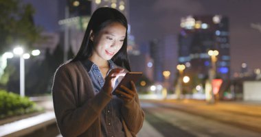 Geceleri cep telefonu kullanan bir kadın. 