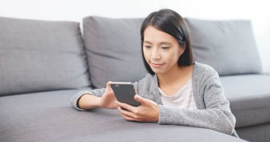 Evde akıllı telefon kullanan bir kadın. 