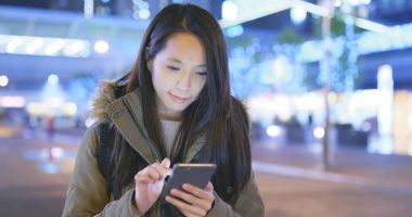 Gece şehirde akıllı telefon kullanan bir kadın. 