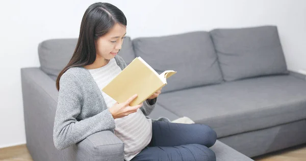 怀孕妇女读书和坐在沙发上 — 图库照片