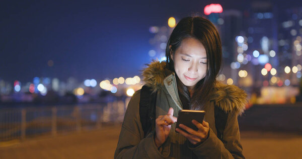 Asian woman using mobile phone in city at night 
