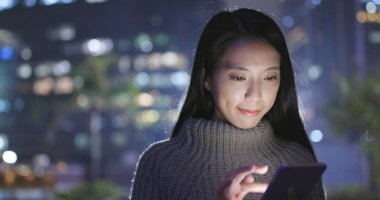 Geceleri cep telefonu kullanan bir kadın. 