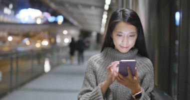 Trafik yol arka plan ile gece şehirde Smartphone kullanan kadın 