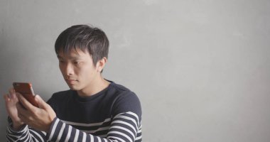 Gri arka plan üzerinde akıllı telefon kullanan adam 