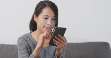 Evde cep telefonu kullanan bir kadın 