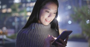 Geceleri cep telefonu kullanan bir kadın. 