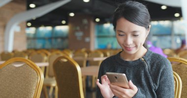 Kafede akıllı telefon kullanan bir kadın. 