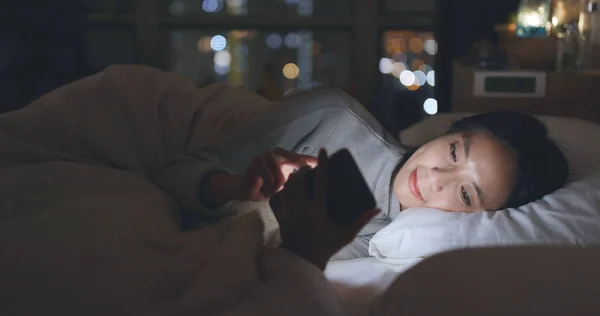 Wanita Mengirim Sms Pada Ponsel Dan Berbaring Tempat Tidur — Stok Foto