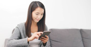 Evde akıllı telefon kullanan bir kadın. 