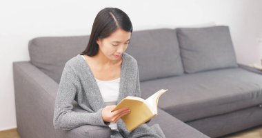 Kitap okuma ve koltukta oturan kadın 