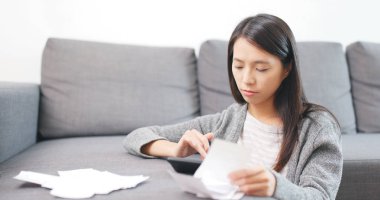 Ev hanımı evde hesap makinesini sayıyor. 