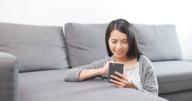 Evde cep telefonu kullanan bir kadın 