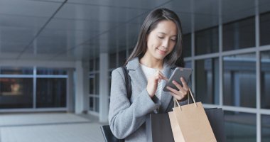 Cep telefonu kullanarak ve kağıt torbalar tutan kadın 