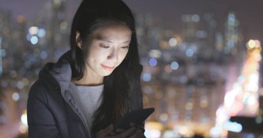 Geceleri şehri cep telefonu kullanan kadın 