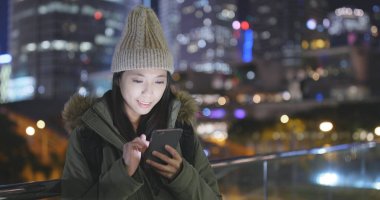 Gece şehirde akıllı telefon kullanan bir kadın. 