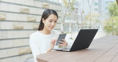 Dizüstü bilgisayar ve cep telefonu açık kahve dükkanında kullanan kadın 