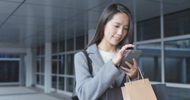 Cep telefonu kullanarak ve kağıt torbalar tutan kadın 