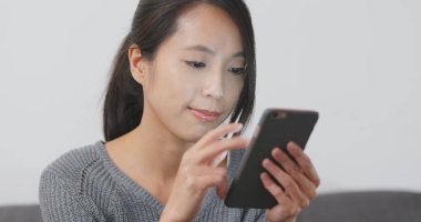 Evde akıllı telefon kullanan bir kadın. 